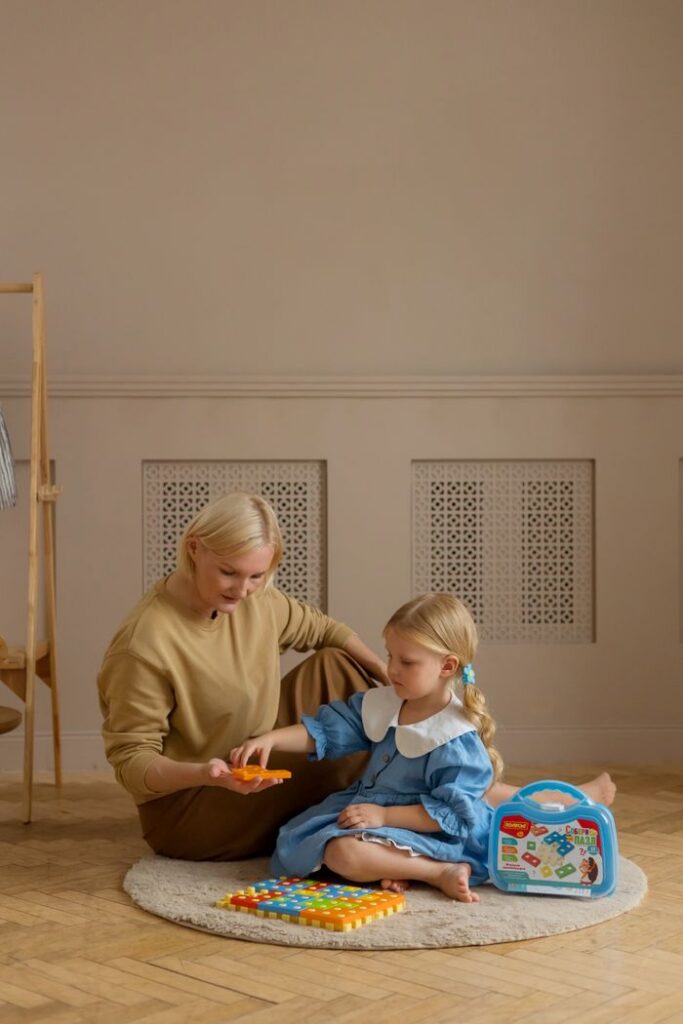 A mother and daughter engage in a fun, educational game sitting indoors.